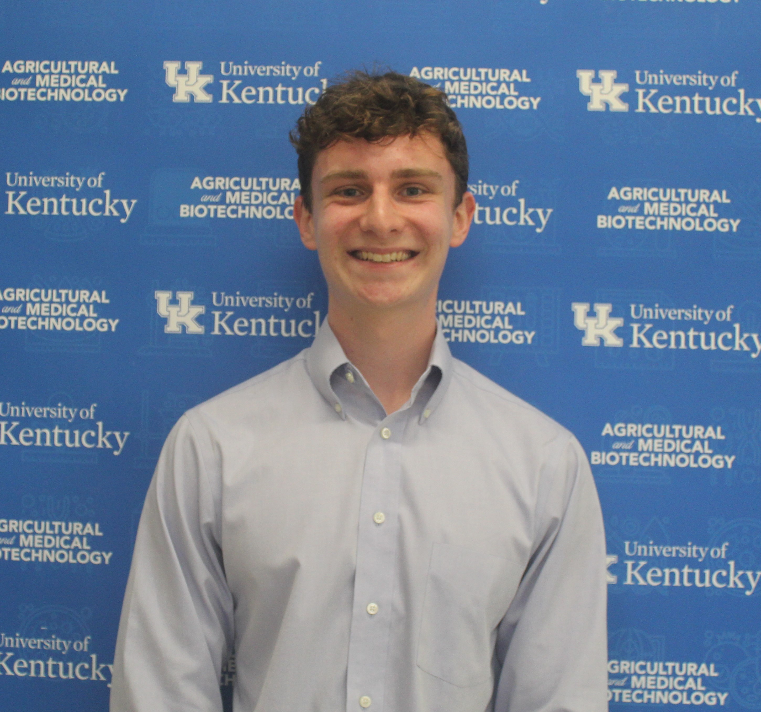 college student standing in front of a blue background 